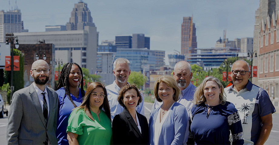 The Vella Group team with Detroit skyline in background